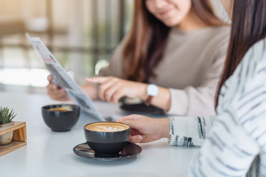 Closeup image of women talking, reading newspaper and drinking coffee  together in the morning