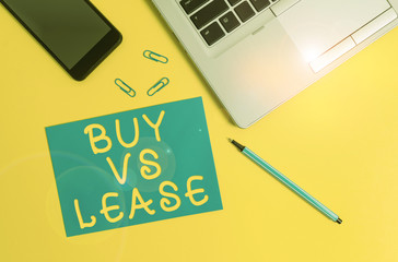 Conceptual hand writing showing Buy Vs Lease. Concept meaning Own something versus borrow it Advantages Disadvantages Trendy open laptop smartphone marker paper sheet clips