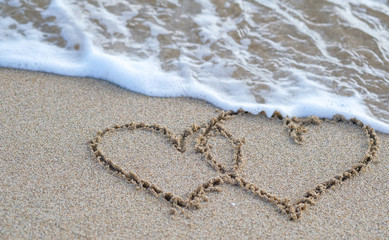 Hand drawn two Hearts on a golden sand. Drawing in sand for Happy Valentines Day, wedding, Love inspirational quote. Romantic love concept. Expression of emotions. Couple of hearts with copy space.