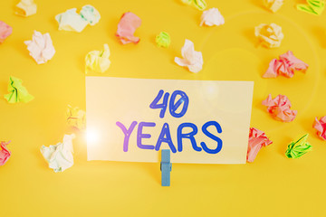 Handwriting text writing 40 Years. Conceptual photo Remembering or honoring special day for being 40 years in existence Colored crumpled papers empty reminder white floor background clothespin