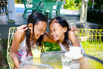 Happy and Cheerful Asian Little Girls in Swimsuit Smiling, Laughing and Embracing Each Other Spending Time Together Outdoor