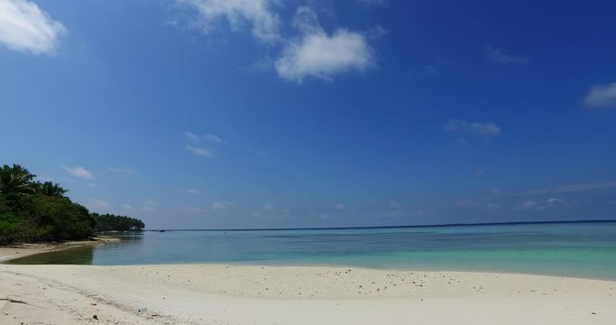 Quite bay with white sandy beach washed by calm sea water under big clear blue sky with few clouds hanging over coastline in Malaysia