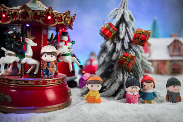 Christmas and New Year holidays concept. Little decorative cute small houses in snow at night in winter, Fir tree standing on snow with beautiful holiday decorated background