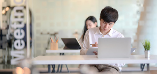 Young professional male designer working on his project while using laptop computer