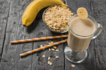 Two orange cocktail tubes next to a glass of banana oatmeal smoothie. Vegetarian smoothie.