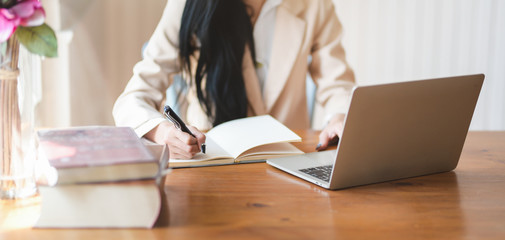 Cropped shot of businesswoman working on her project while writing the idea on notebook