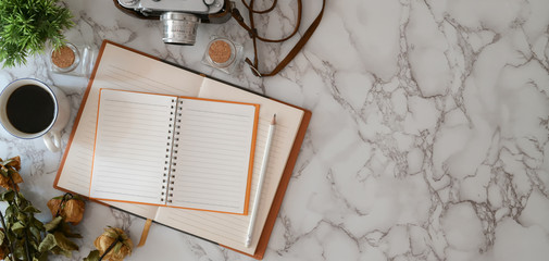 Overhead shot of modern workplace with open notebook and office supplies on marble desk with copy space