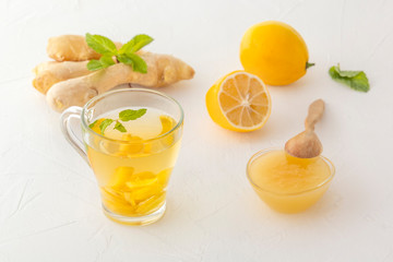 Ginger tea with lemon, honey and mint on a white wooden table