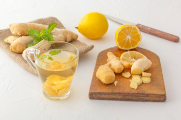 Ginger tea with lemon, honey and mint on a white wooden table