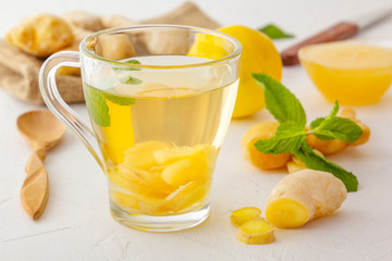 Ginger tea with lemon, honey and mint on a white wooden table. Close-up