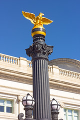 Eagle statue near the Union Station building in Washington DC. A street lamp decorated by a golden eagle statue under a clear blue sky.
