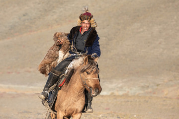 Naklejka premium Kazakh eagle hunters partaking in a traditional wrestling match. Two wrestlers on horseback start pulling on a sheep skin, the one who retrieves it, is the winner. Ulgii, Mongolia.