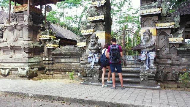 Young tourist couple waiting to open door of Asian ancient temple for visiting beautiful spiritual statues and gardens of temple in Thailand