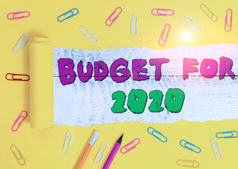 Word writing text Budget For 2020. Business photo showcasing An written estimates of income and expenditure for 2020 Stationary and torn cardboard placed above a wooden classic table backdrop