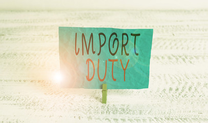 Word writing text Import Duty. Business photo showcasing tax imposed by a government on goods from other countries Green clothespin white wood background colored paper reminder office supply