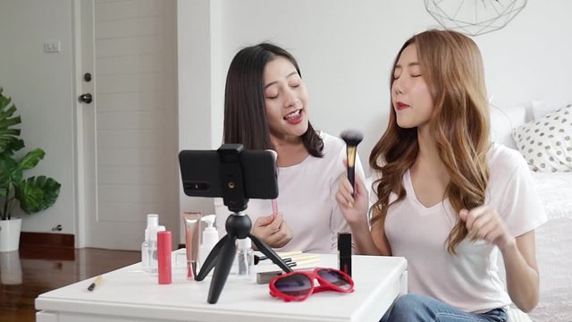 Portrait of young asian woman review giveaway gift product fan following channel, recording video make up lipstic cosmetic at home. Beauty blogger present beauty cosmetics