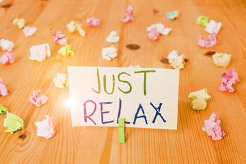 Conceptual hand writing showing Just Relax. Concept meaning to rest or do something that is enjoyable and stress free Colored crumpled papers wooden floor background clothespin