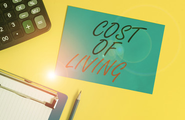 Writing note showing Cost Of Living. Business concept for The level of prices relating to a range of everyday items Clipboard blank sheet square page calculator pencil colored background