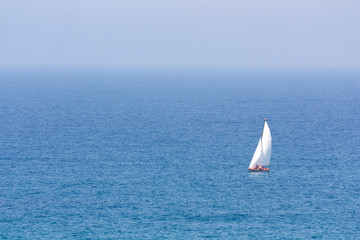 Seascape with white sailing boat and the haze on the horizon