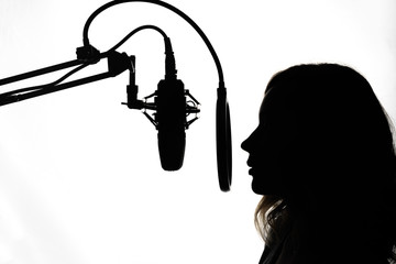 Silhouette of a girl with a studio microphone, radio presenter, singer and blogger, voice acting for films. Strong, black and white photo