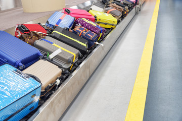 Colorful suitcases and bags on luggage conveyor belt in airport