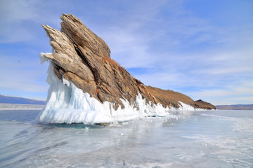 Baikal Lake, Monster Rock or Okoy Rock over frozen water against cloudy blue sky, Olkhon Islan, Irkutsk, Russia