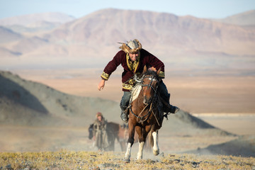 Traditional Mongolian game where a rider on horseback aims to pick up a napkin from the ground at...