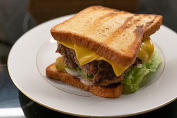 Homemade sandwich with large juicy beef Patty and salad on the plate closeup. Selective focus