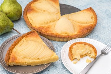 Delicious home bake poached pear tart pie, as known as Tarte Bourdaloue, a cup of coffee latte. It is a french popular recipe that gets the name from a street in Paris. Food on table concept.