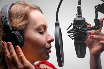 Singer or radio host working in a recording studio with a microphone in headphones close-up,...