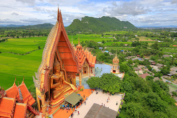 Panorama view of Wat Tham Suea with Golden big buddha statue and background of mountain and rice...
