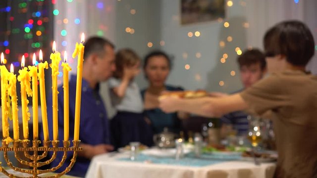 Blurred image happy Jewish family having dinner party at home. Hanukkah menorah lights. Celebration, holidays and people concept