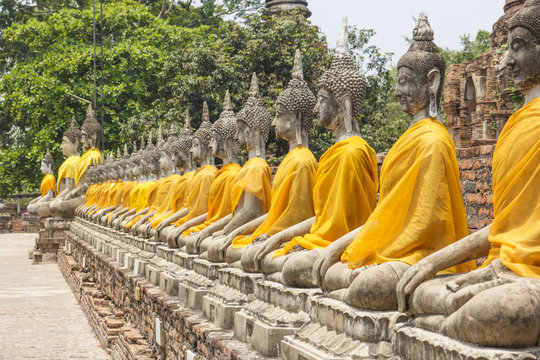 Buddha statue in row with background of ruin pagoda at The temple of Wat Yai Chai Mongkol in Ayutthaya near Bangkok, Thailand