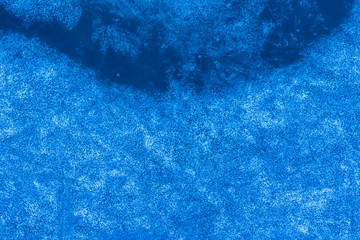 blue texture of an ice surface with pure azure water ,cold snow cryslallized wall background ,winter frozen lake side close up , abstract macro wallpaper