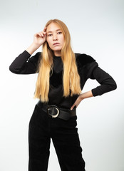 Blonde in black clothes on a gray background.