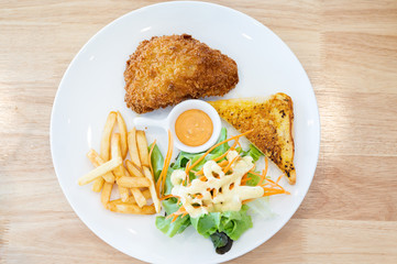 Top view grilled fish steak set in white dish on wooden table background.Salmon steak, french fries, bread and salad.Restaurant menu.