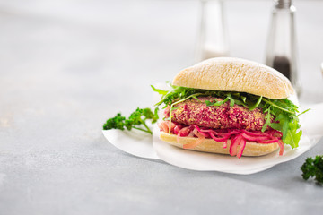Vegetarian burger with beetroot patty, fermented onions and arugula on white background with place for your text