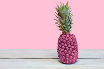 Creative pineapple pink color, pink wall and wooden table.