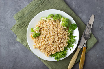 Boiled spelt on a plate. Healthy food. Gray concrete background. Top view.