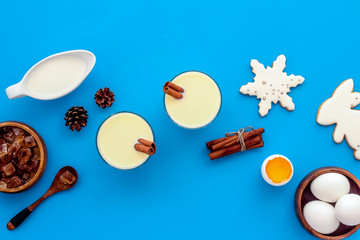 Ingredients for New Year drink eggnog - eggs, milk, cinnamon on blue background top view copy space