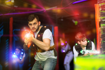 Emotional guy playing laser tag in colorful beams