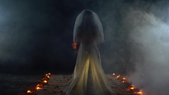 A ghost bride surrounded by candles standing in a dark scary room. Halloween concept. Dolly forwards. Horror creepy concept, Dia de los Muertos