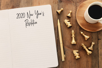 Naklejka na ściany i meble Business concept of top view 2020 year's resolution list with notebook, cup of coffee over wooden desk