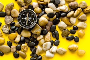 Sea journey, travelling and vacation concept. Compass on rocks and yellow background top view