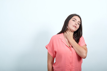 Tired caucasian young woman in pink shirt isolated on white background in studio holding hand on neck with closed eyes. People sincere emotions, lifestyle concept.