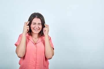 Cheerful caucasian woman in pink shirt isolated on white background in studio holding fingers crossed, waiting for special moment. People sincere emotions, lifestyle concept.