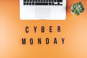The words CYBER MONDAY on a bright orange background with a laptop.