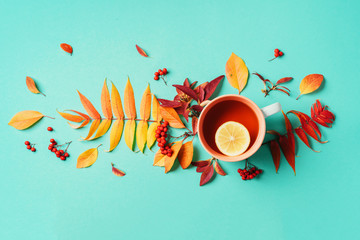 Autumn flat lay composition. Cup of tea, autumn bright leaves on blue background. Top view. Flat...