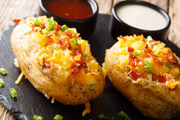 Tasty hot stuffed potatoes with cheddar cheese, green onions and bacon close-up. horizontal