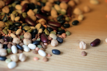 Different beans scattered on a wooden surface close-up. Naturel organic food background